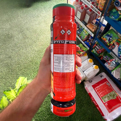 Red bottle held in a hand with a grocery store background