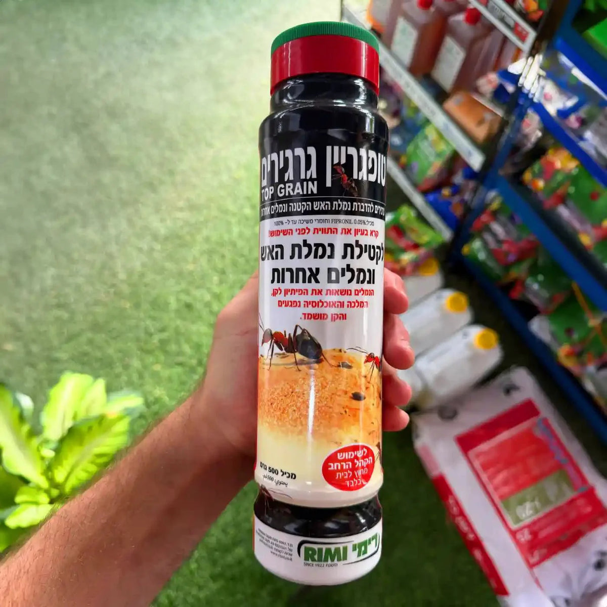 Hand holding a bottle of Rimi brand ant killer in a grocery store setting